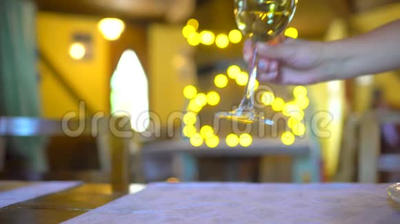 在假日波克闪烁背景餐厅的玻璃中的白葡萄酒录像服务员的手放了一个玻璃杯视频的预览图