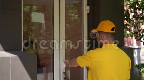 穿黄色制服的快递员在门口给女人送披萨盒视频的预览图
