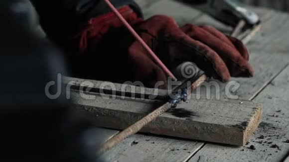 侧视焊机在焊接面罩焊接两个金属零件穿工作服的工人在室内工作视频的预览图