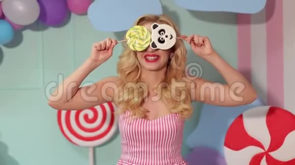 快乐的女孩用两个大棒棒糖遮住她的脸视频的预览图
