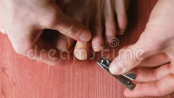 男人用钳子把指甲整齐地剪在脚上一个男人在家里做足疗在地板上在顶部视频的预览图