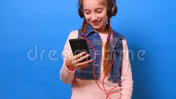 戴着耳机看手机屏幕的小女孩微笑着视频的预览图