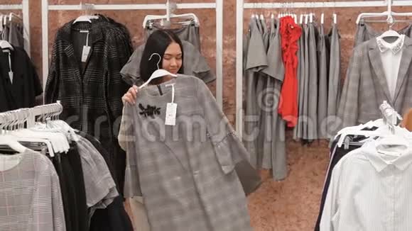 年轻女子在服装店挑选一件衣服并与她的朋友商量在镜子里试衣服女孩视频的预览图