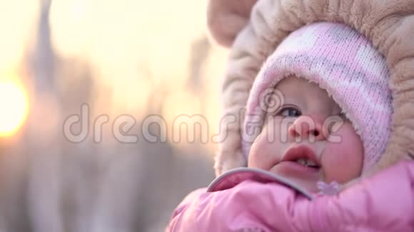 冬天女孩微笑的特写镜头公园冬天穿粉色连衣裙的快乐好奇女婴视频的预览图