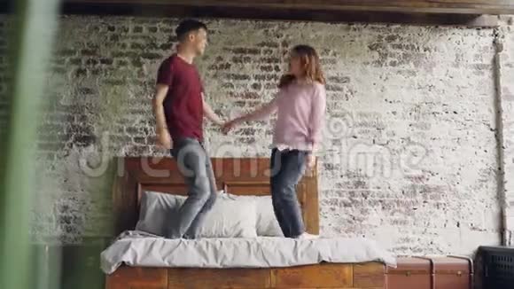 年轻的女朋友和男朋友正在双人床上跳舞在卧室里亲吻在一起玩得开心快乐活跃的人视频的预览图