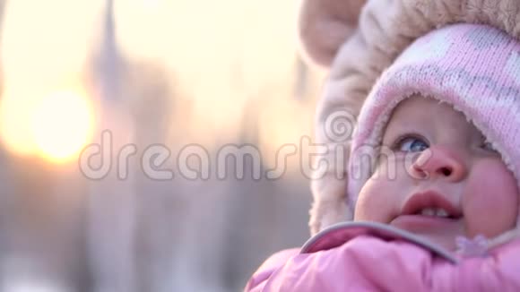 冬天女孩微笑的特写镜头公园冬天穿粉色连衣裙的快乐好奇女婴视频的预览图