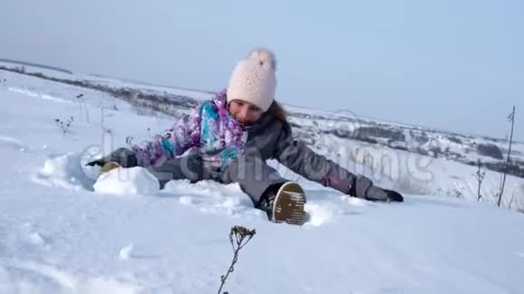 小女孩坐在雪地里玩得很开心视频的预览图