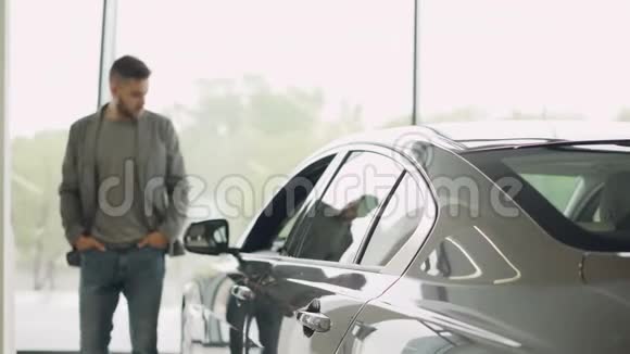 有兴趣的顾客正在汽车陈列室检查漂亮的汽车看着汽车摸着它专注于闪亮视频的预览图