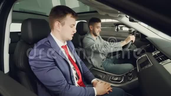 开朗的买车人正在和坐在昂贵的汽车和触摸仪器里的专业销售人员交谈视频的预览图