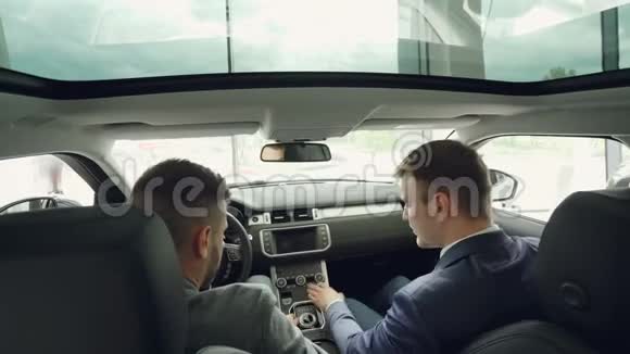 从高角度看汽车经销商工人与客户交谈坐在商务舱内触摸控制面板和视频的预览图