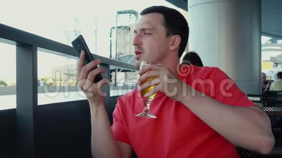 放松的男人在智能手机上喝酒聊天视频的预览图