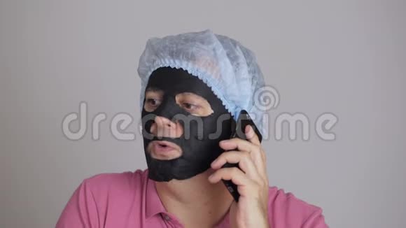 一位45岁的男子脸上戴着一个恢复活力的黑色组织化妆面具打着电话视频的预览图