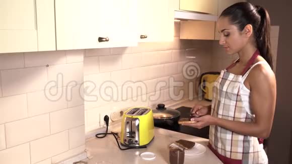 女孩站在厨房靠近炉子在一块油炸面包上润滑坚果她用刀子来做这个女人是视频的预览图