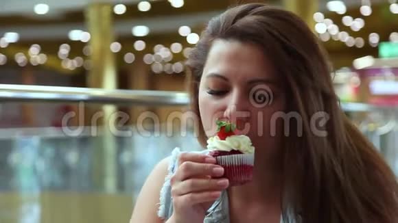 一个漂亮的女孩在一家咖啡馆里坐在桌子旁吃一个甜蛋糕心情很好视频的预览图