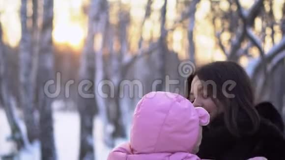 在户外穿着连衣裙抱着孩子的女人冬季背景下穿粉色连衣裙的年轻女性的特写视频的预览图