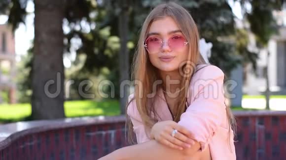 可爱的少女长着一头金发坐在公园里视频的预览图