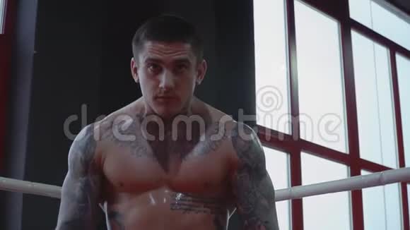 有纹身的英俊的拳击手站在戒指的角落里视频的预览图