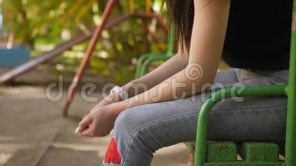 一个悲伤的女孩坐在操场上黑发的肖像中弹视频的预览图