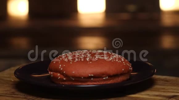 新鲜汉堡包的特写芝麻放在黑色盘子上在木板上旋转库存数据视频的预览图