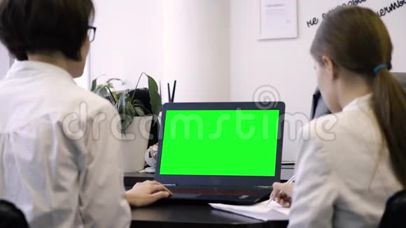 查看员工和绿色笔记本电脑屏幕从后面的办公室工作人员的笔记本电脑与绿色屏幕概念视频的预览图