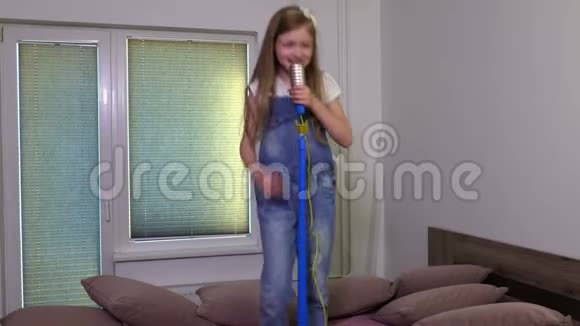 带着玩具麦克风在床上跳舞唱歌的微笑女孩视频的预览图