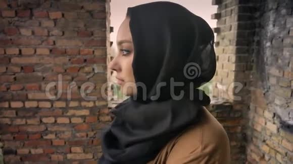 年轻悲伤的穆斯林妇女戴着头巾站在废弃的大楼里转过身来看着摄像机吓坏了视频的预览图