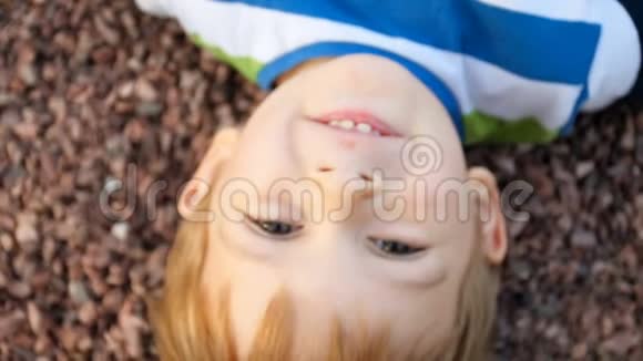 从上面看到可爱的微笑的幼儿男孩躺在地上看着相机视频的预览图