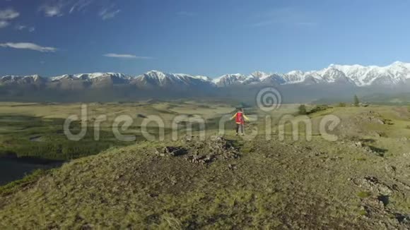 空中近距离女性徒步旅行者自豪地站在山上在夏天站在上面的年轻女子背着一个红色背包视频的预览图