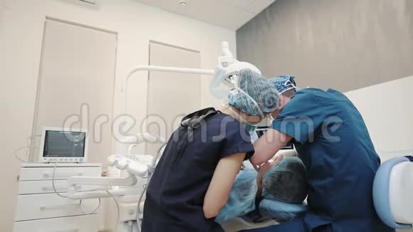 两名医生和病人坐在牙科诊所的椅子上视频的预览图