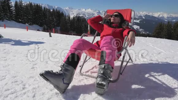 冬天坐在山上的一个阳光休息室里的女人享受阳光的天气视频的预览图