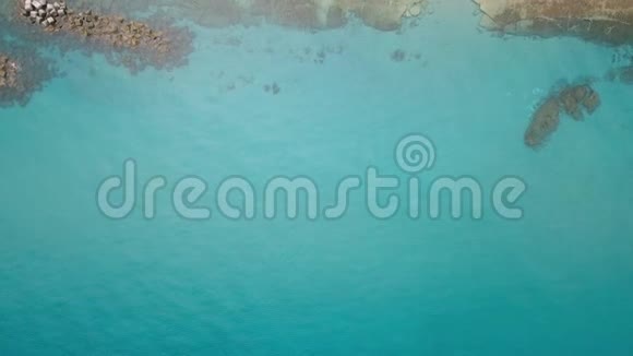 海上海岸的鸟瞰图波浪在石滩附近飞溅蔚蓝的清水视频的预览图