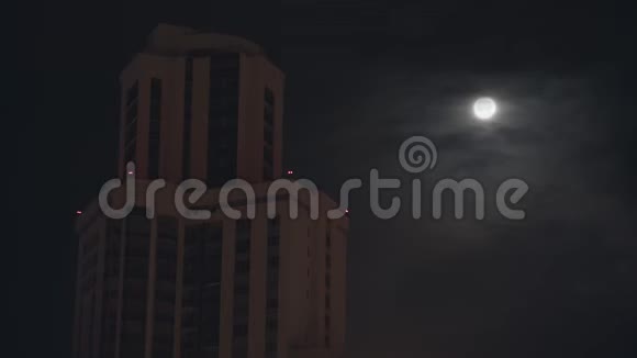夜晚的城市景观在黑暗的天空背景上有一座高楼库存录像乌云密布的天空上有满月视频的预览图
