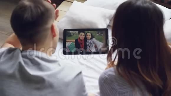 丈夫和妻子在网上和朋友聊天通过平板电脑打视频电话屏幕上的活泼女人正在显示视频的预览图