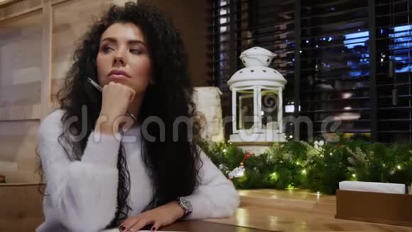 穿着白色毛衣的可爱黑发作家喜欢被冬天的咖啡馆包围视频的预览图
