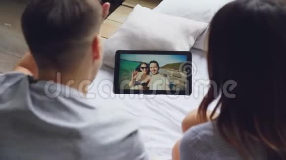 已婚夫妇正在用平板电脑在skype上和朋友聊天快乐的恋人在屏幕上笑着接吻视频的预览图