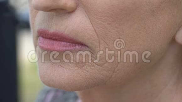 老妇人摸着皱纹的脸皮肤老化渴望年轻视频的预览图