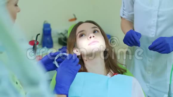 牙医与助理准备女孩美白牙齿美白程序视频的预览图