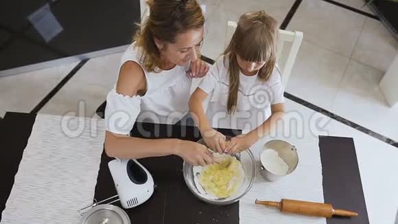 上景女人为海绵蛋糕混合配料她是由一个小女儿帮助的小女孩高兴地吃鸡蛋视频的预览图