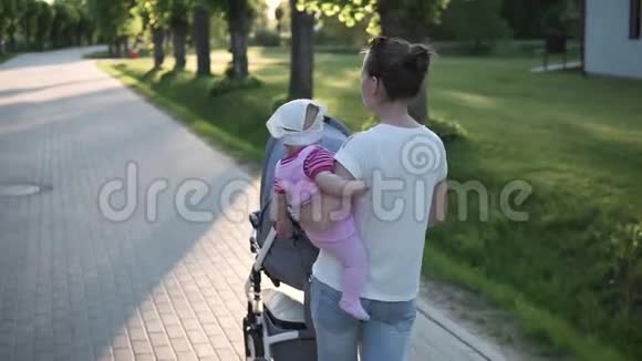 妈妈手里拿着婴儿走路阳光明媚带着婴儿车视频的预览图