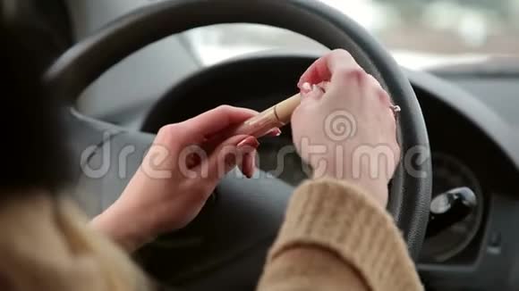 女孩打开口红坐在汽车的车轮后面视频的预览图