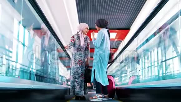 年轻的穆斯林女孩坐在自动扶梯上谈笑风生视频的预览图