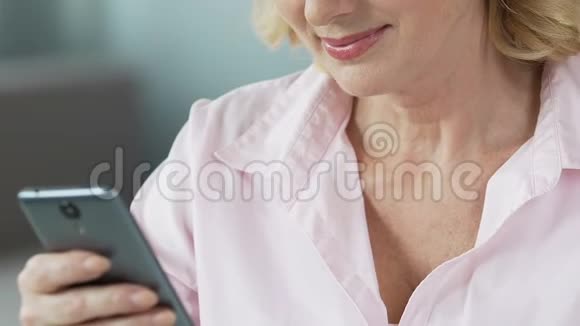 漂亮的中年女性在智能手机上观看儿童照片特写视频的预览图