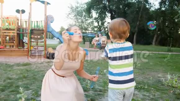 4k视频快乐的大笑男孩追着他妈妈在公园吹的肥皂泡跑视频的预览图