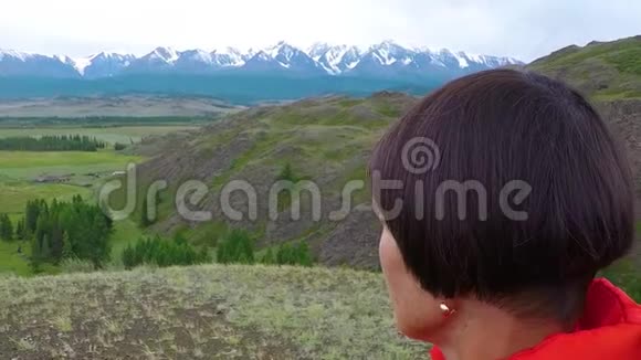 在寒冷的阴天女徒步旅行者骄傲地站在山顶上站在山顶上的女人近距离空中飞行视频的预览图