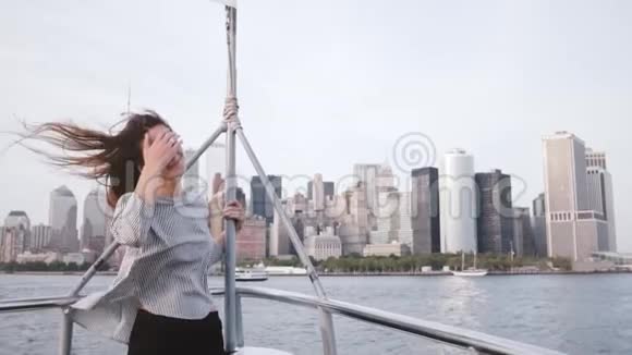美丽的兴奋的旅行女孩她的头发和手臂张开在旅游船上缓慢地看着纽约的天际线视频的预览图