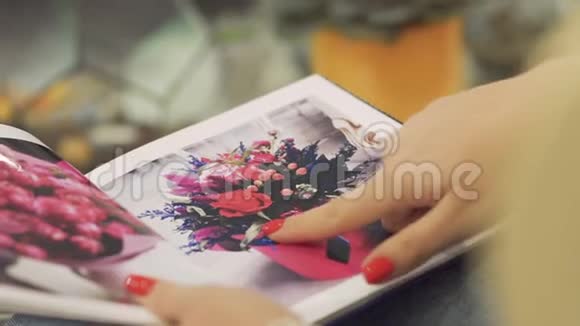 一只红色美甲的女性手靠近女性手指滑过植物区系小册子视频的预览图