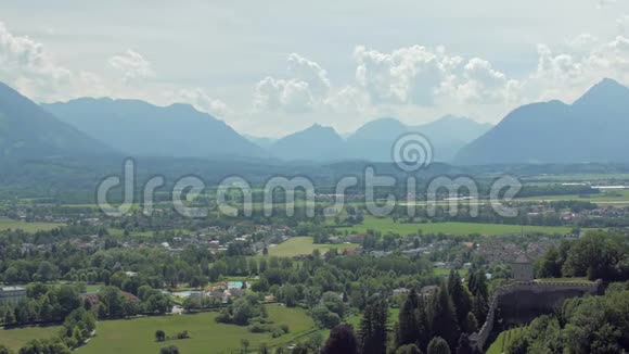 在萨尔茨堡市附近的阿尔卑斯山山脉的底部有小房子的绿色草地上令人惊叹的景观视频的预览图