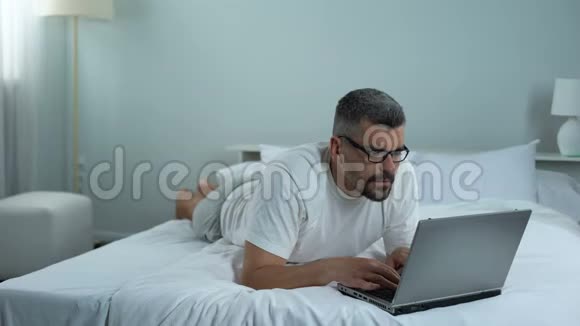 男人揉着眼睛厌倦了笔记本电脑自由职业者在做项目最后期限的压力视频的预览图