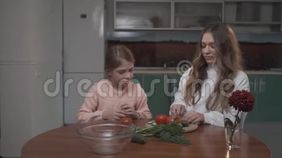 小妹妹在舒适的小桌子旁帮助姐姐准备蔬菜沙拉作为早餐视频的预览图