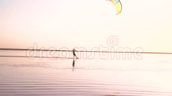 一个戴着头盔的人在湖面上控制着一只训练风筝在黎明时玩极端的把戏视频的预览图